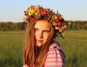 A blond girl with floral crown in a field.