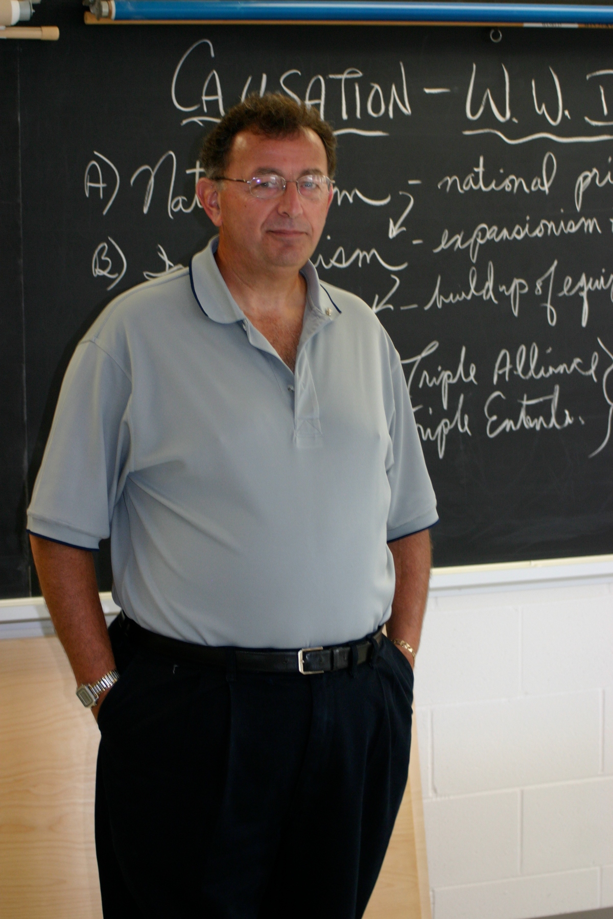 John Fioravanti is standing in front of the blackboard in his classroom.